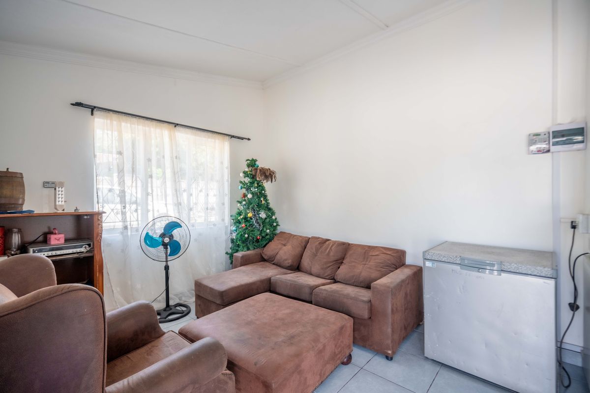 A living room area featuring tiled flooring and a window with a curtain rod, offering a functional space for relaxation.