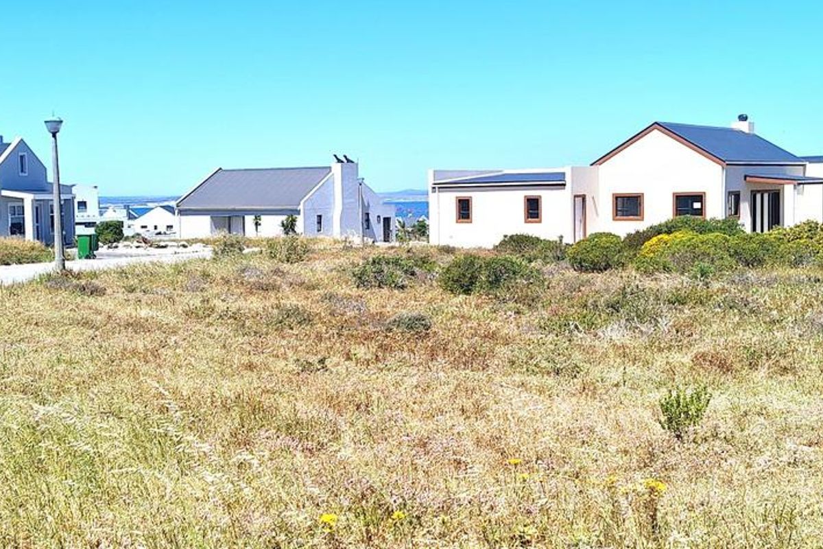 A view of a vacant residential plot in a developed coastal estate, featuring surrounding modern homes and established infrastructure.