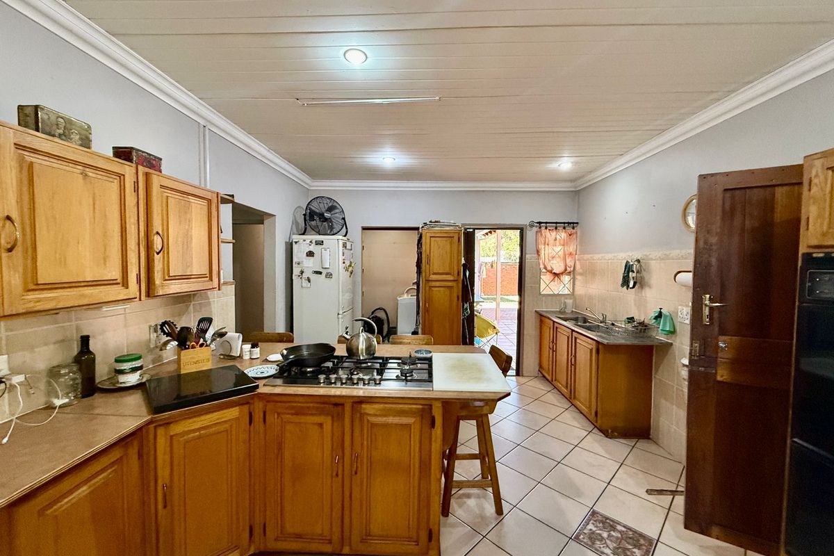 A functional kitchen featuring wooden cabinetry, a built-in gas hob, tiled flooring, and direct access to an outdoor area.