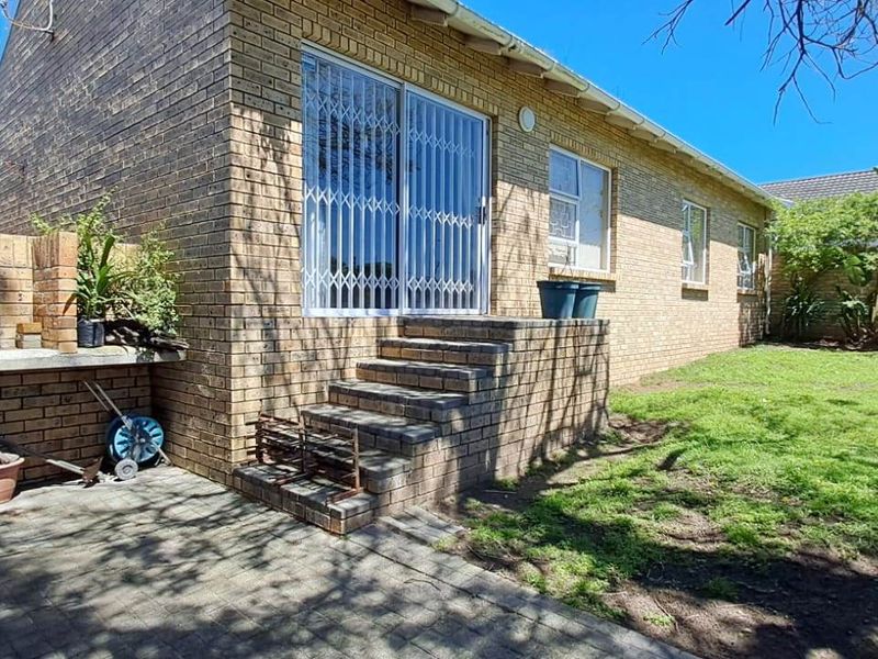 Rear exterior view of the townhouse featuring a brick facade, paved patio area with built-in brick counter, and a private garden space.