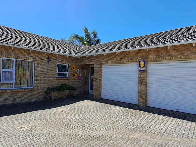 Front exterior view of a brick townhouse featuring a double garage, paved driveway, and tiled roof.