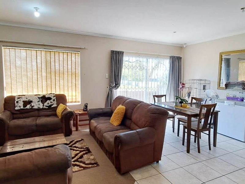 Spacious open-plan living and dining area featuring tiled flooring, large sliding doors with security gates, and neutral wall finishes.