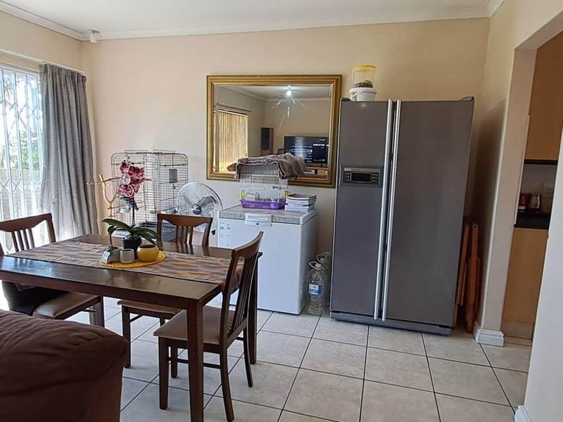 Open plan living and dining area featuring tiled flooring and a sliding glass door with security gate leading to the exterior.
