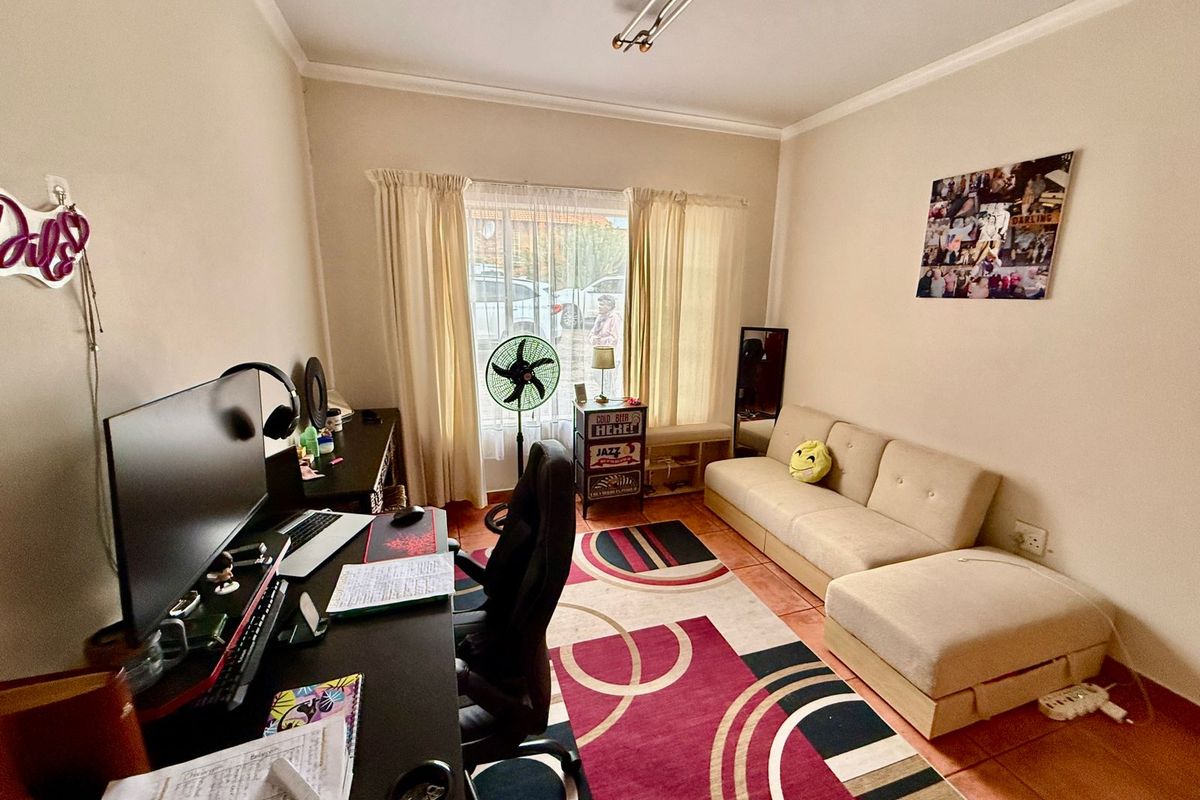 A functional living room space featuring tiled flooring, neutral wall finishes, and a large window providing natural light.