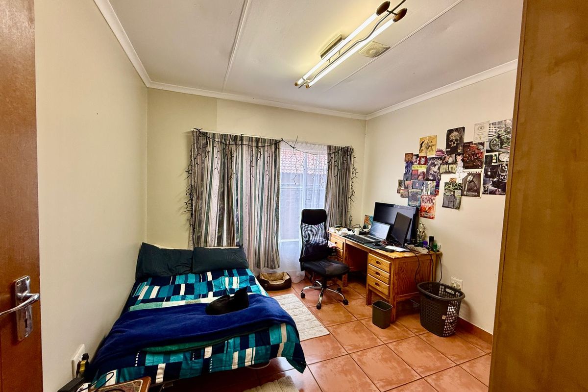 A functional bedroom featuring tiled flooring, a central ceiling light fixture, and a window with curtain tracks.