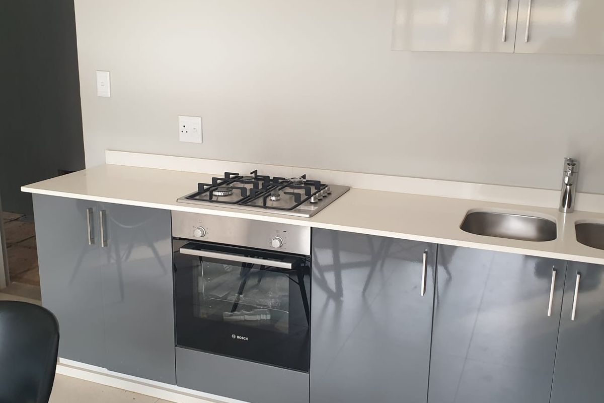 Modern kitchen featuring sleek grey gloss cabinetry, white quartz countertops, a built-in Bosch oven, and a gas hob.