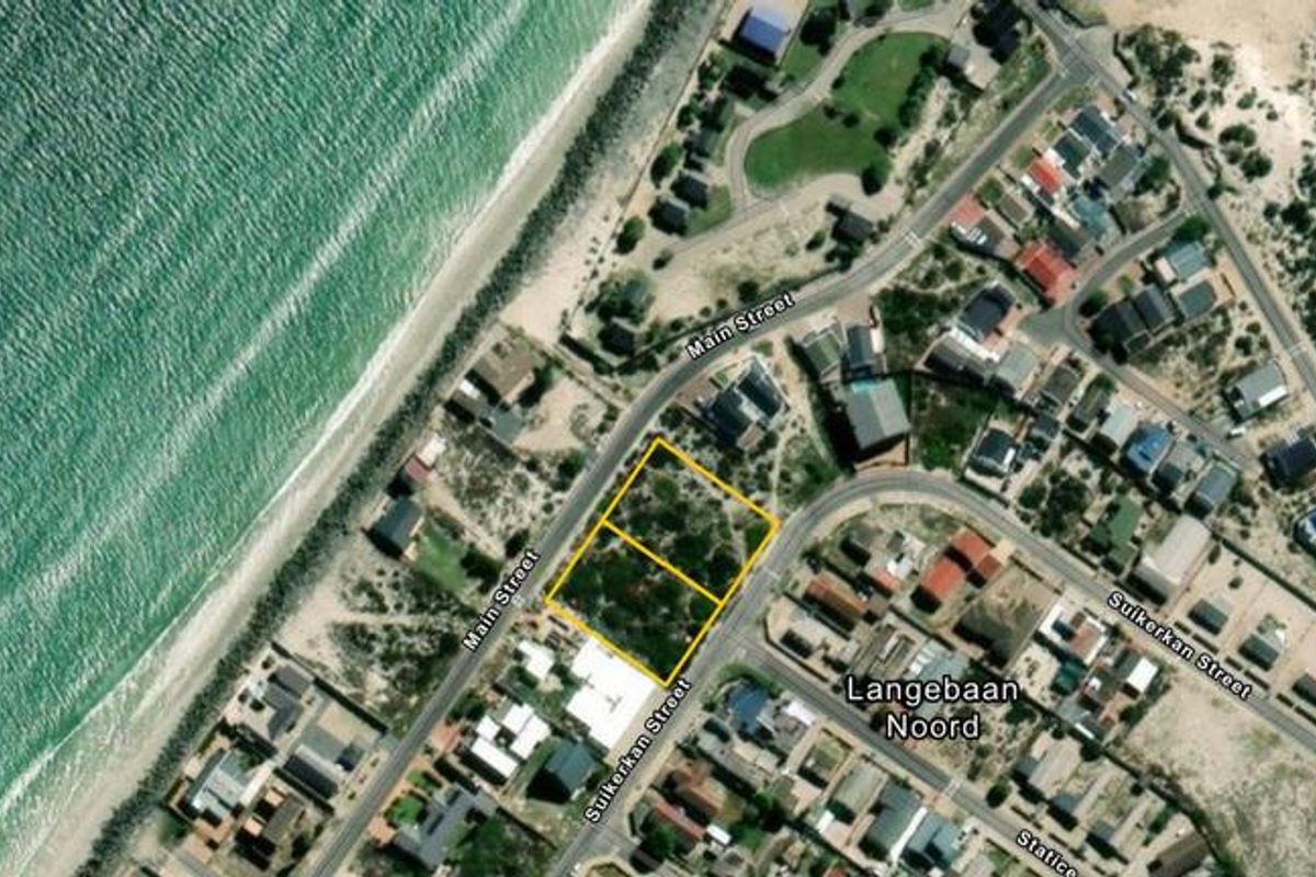 Aerial view of a vacant residential plot situated in a coastal neighborhood, highlighting its proximity to the beach and local street access.