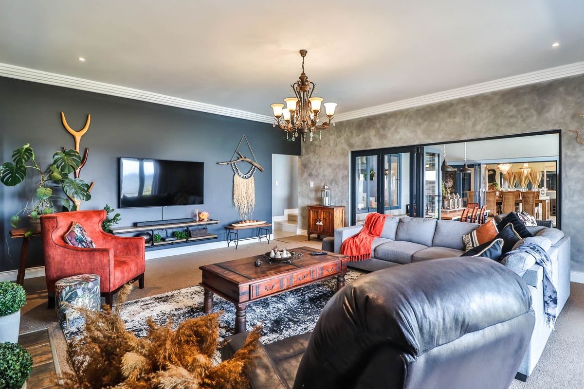 Spacious living room featuring decorative crown molding, recessed lighting, and large glass sliding doors leading to an adjacent dining area.