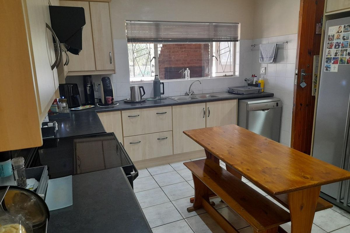 Functional kitchen featuring light wood cabinetry, dark laminate countertops, tiled splashbacks, and a built-in stove with extractor fan.