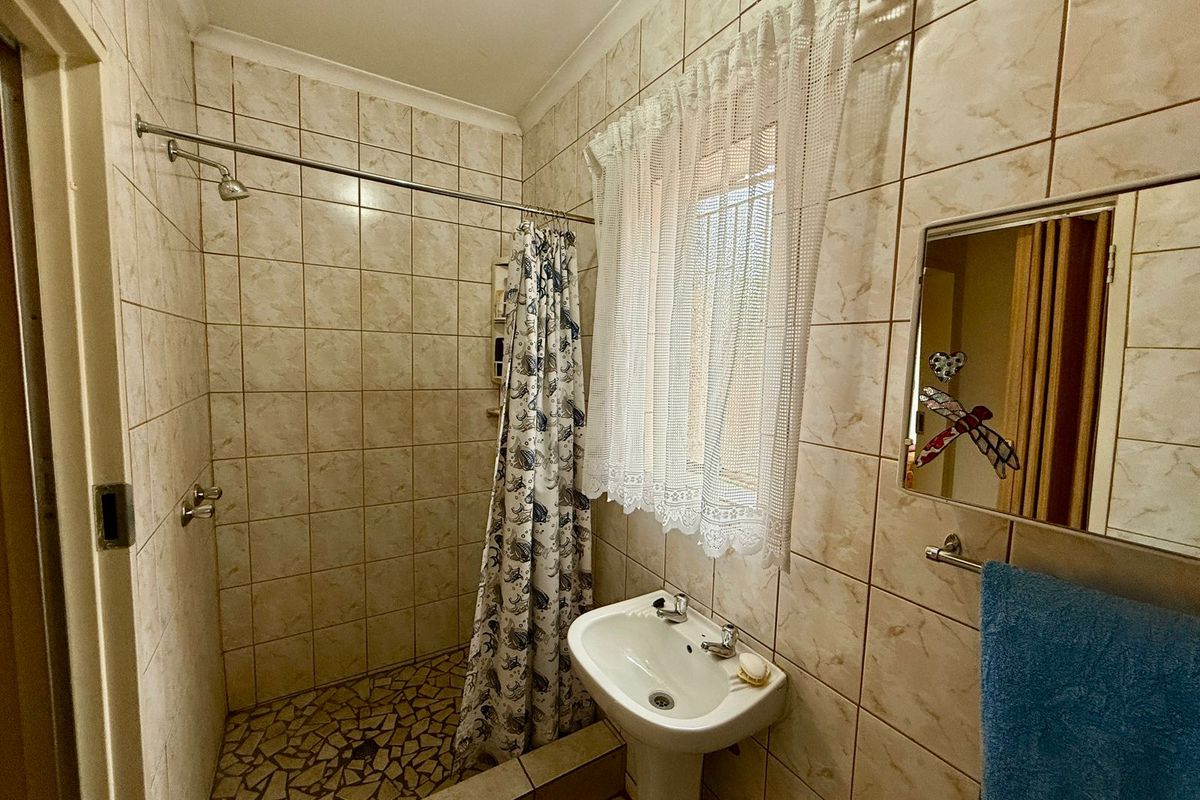 A functional bathroom featuring a walk-in shower with a mosaic tile floor, pedestal basin, and full-height wall tiling.