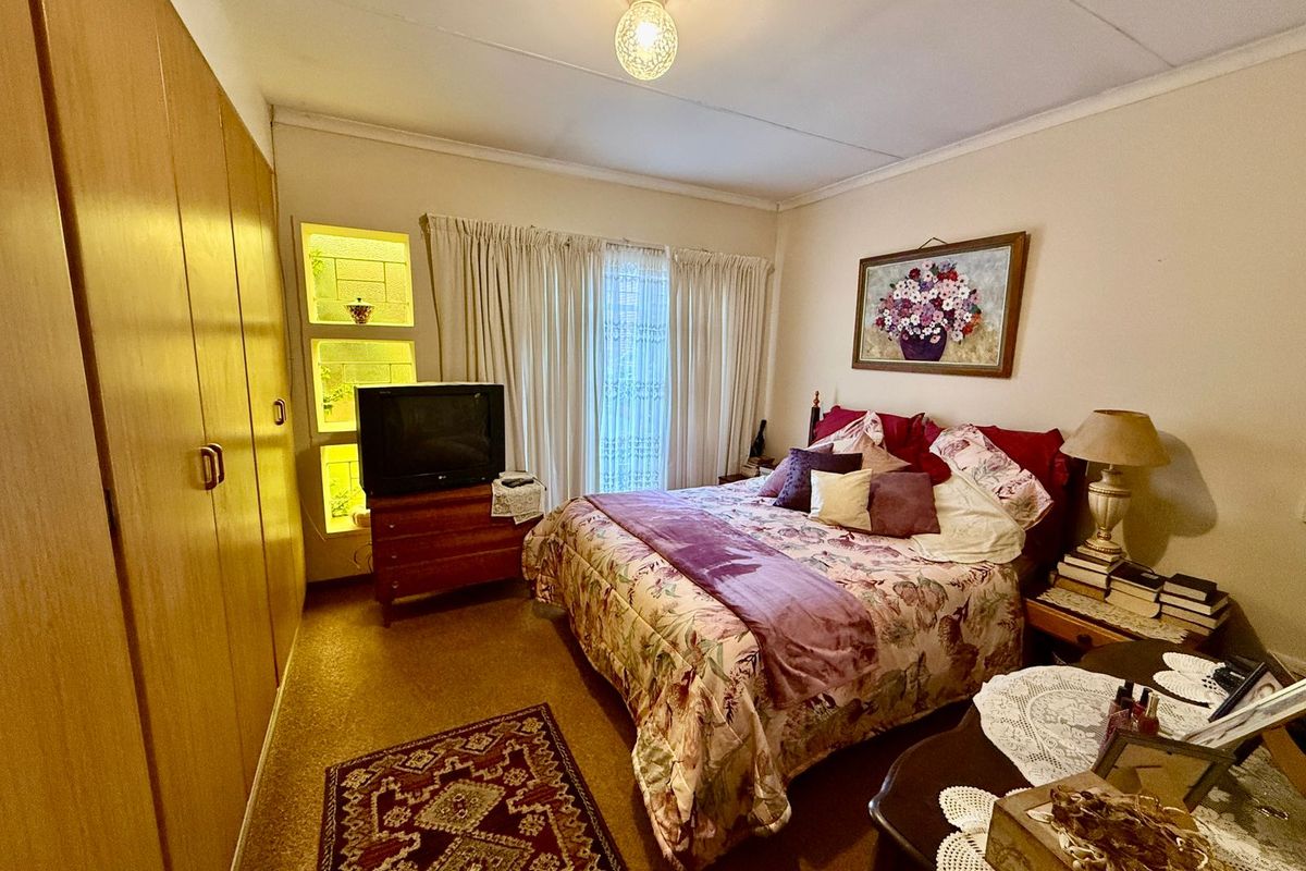 A bedroom featuring built-in wooden cupboards, a decorative glass block feature wall, and carpeted flooring.