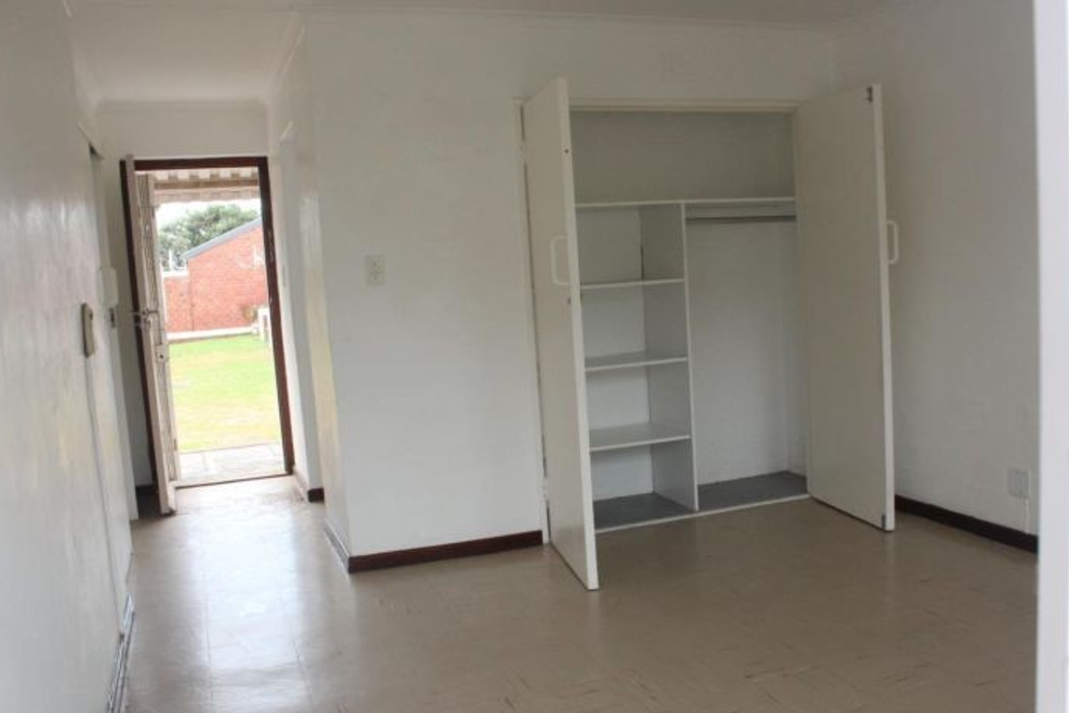 A vacant bedroom featuring built-in storage cabinetry and direct access to an outdoor area.