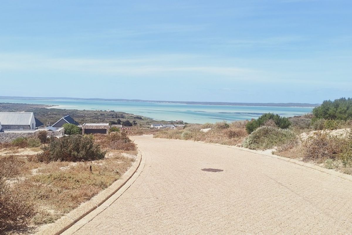 A scenic view of the coastal landscape and lagoon from a paved residential road, showcasing the natural surroundings of the property.