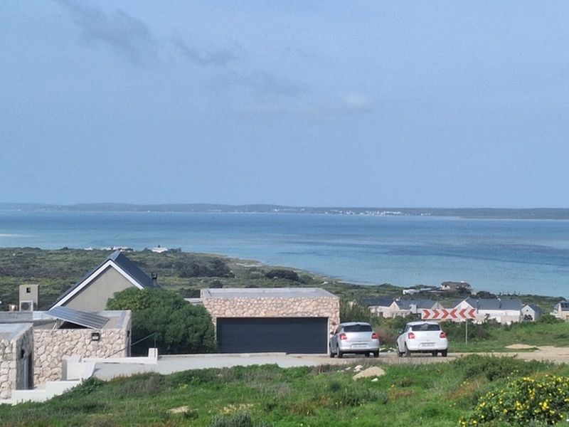 A scenic elevated view overlooking the coastline, featuring nearby residential properties and a clear view of the ocean.