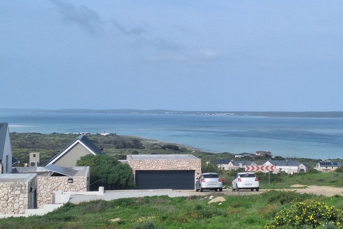 A scenic elevated view overlooking the coastline, featuring nearby residential properties and a clear view of the ocean.