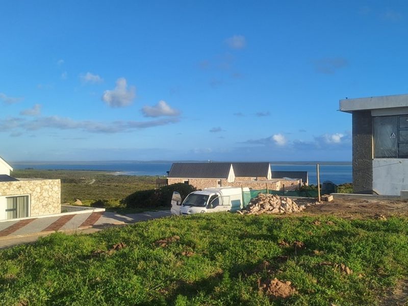 A scenic view overlooking a coastal residential development with modern homes under construction and natural landscape in the foreground.