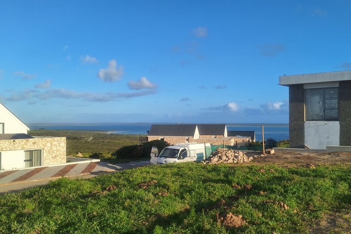 A scenic view overlooking a coastal residential development with modern homes under construction and natural landscape in the foreground.