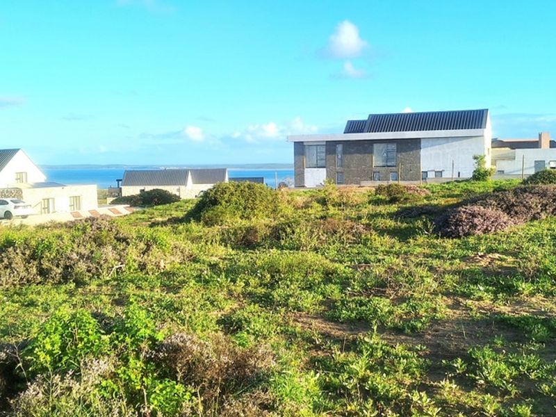 A scenic view of the surrounding residential estate and coastal landscape, showcasing the natural terrain and nearby modern architectural developments.