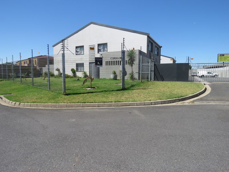 Front exterior view of the apartment complex featuring a secure perimeter with electric fencing, gated access, and a well-maintained lawn.