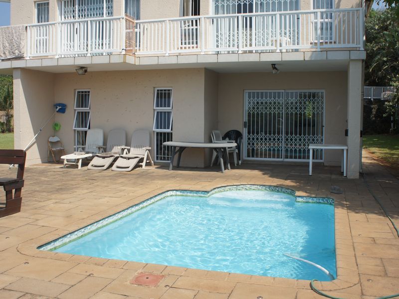 Outdoor pool area featuring a paved patio, swimming pool, and access to the ground floor and upper balcony of the townhouse.