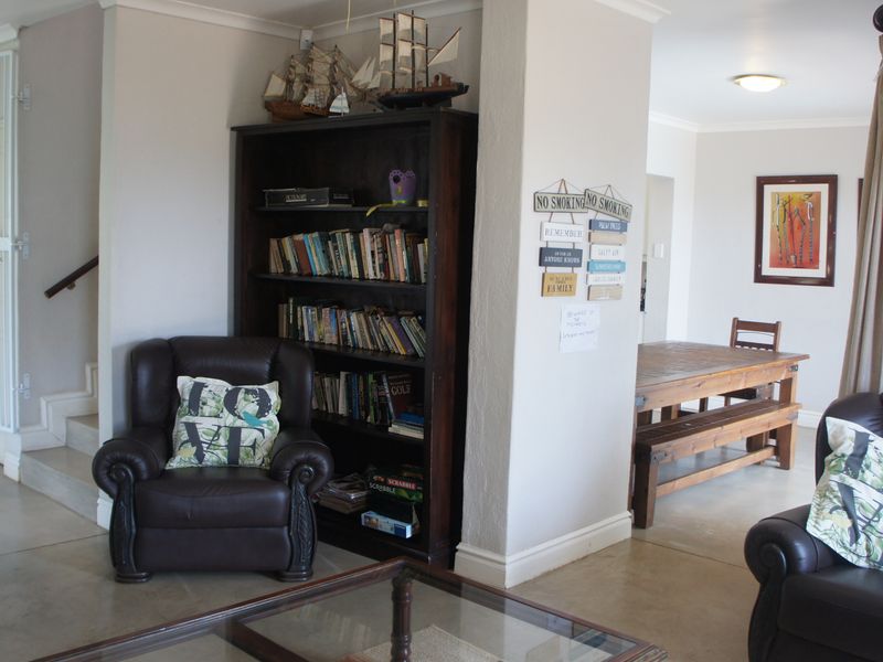 Open plan living and dining area featuring concrete flooring, neutral walls, and a staircase with a security gate.