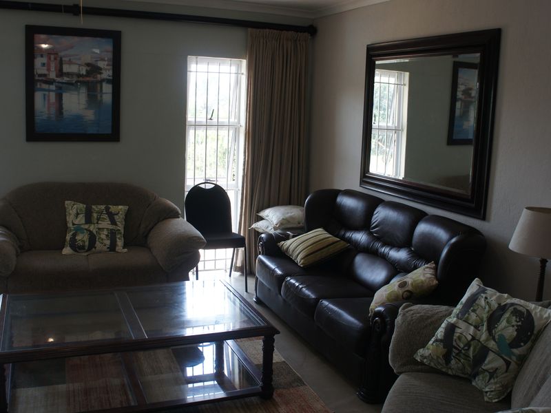 A living room featuring tiled flooring, large windows with security bars, and curtain rails.