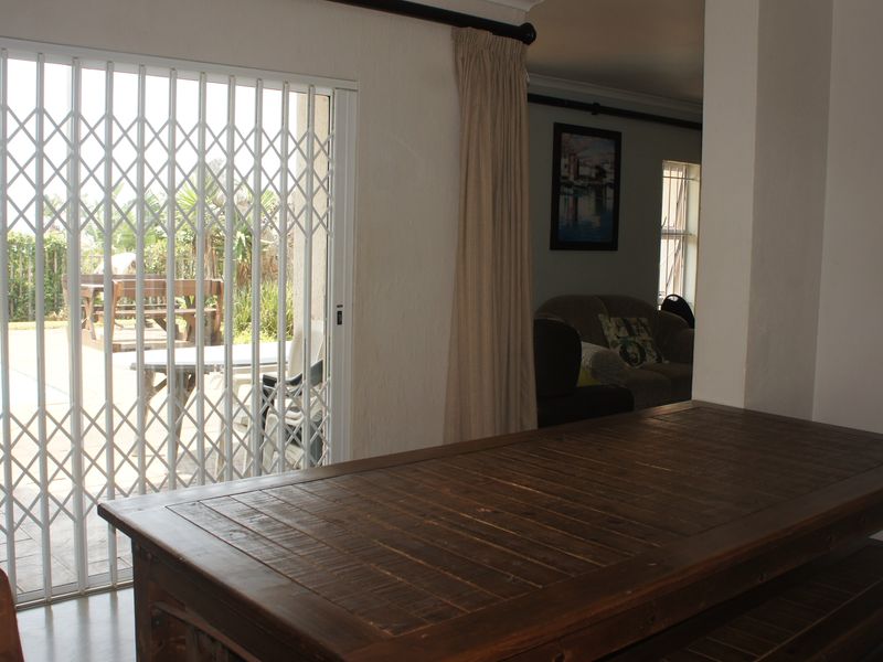Living area featuring a sliding security gate and glass door providing direct access to the outdoor pool area.