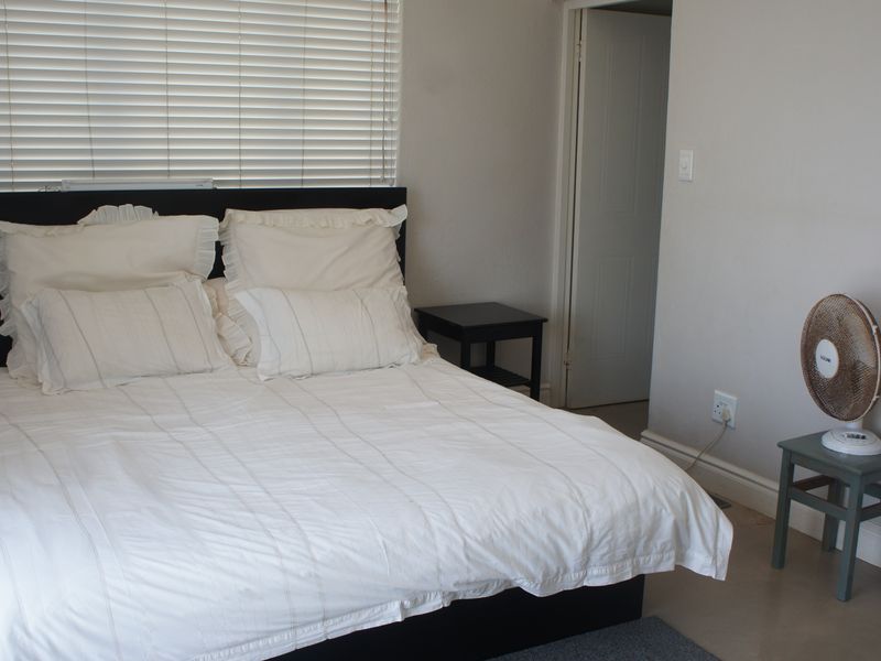 A simple bedroom featuring neutral walls, venetian blinds, and standard interior door access.