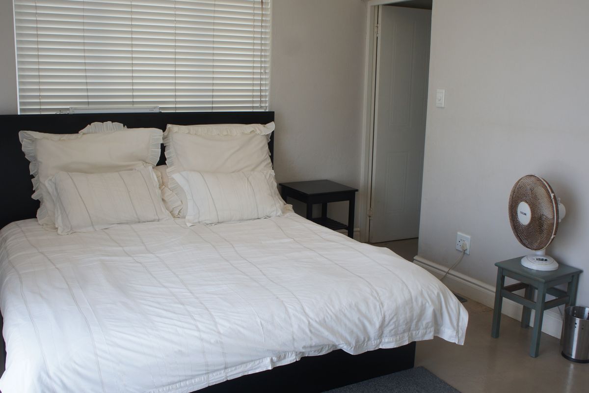 A simple bedroom featuring neutral walls, venetian blinds, and standard interior door access.