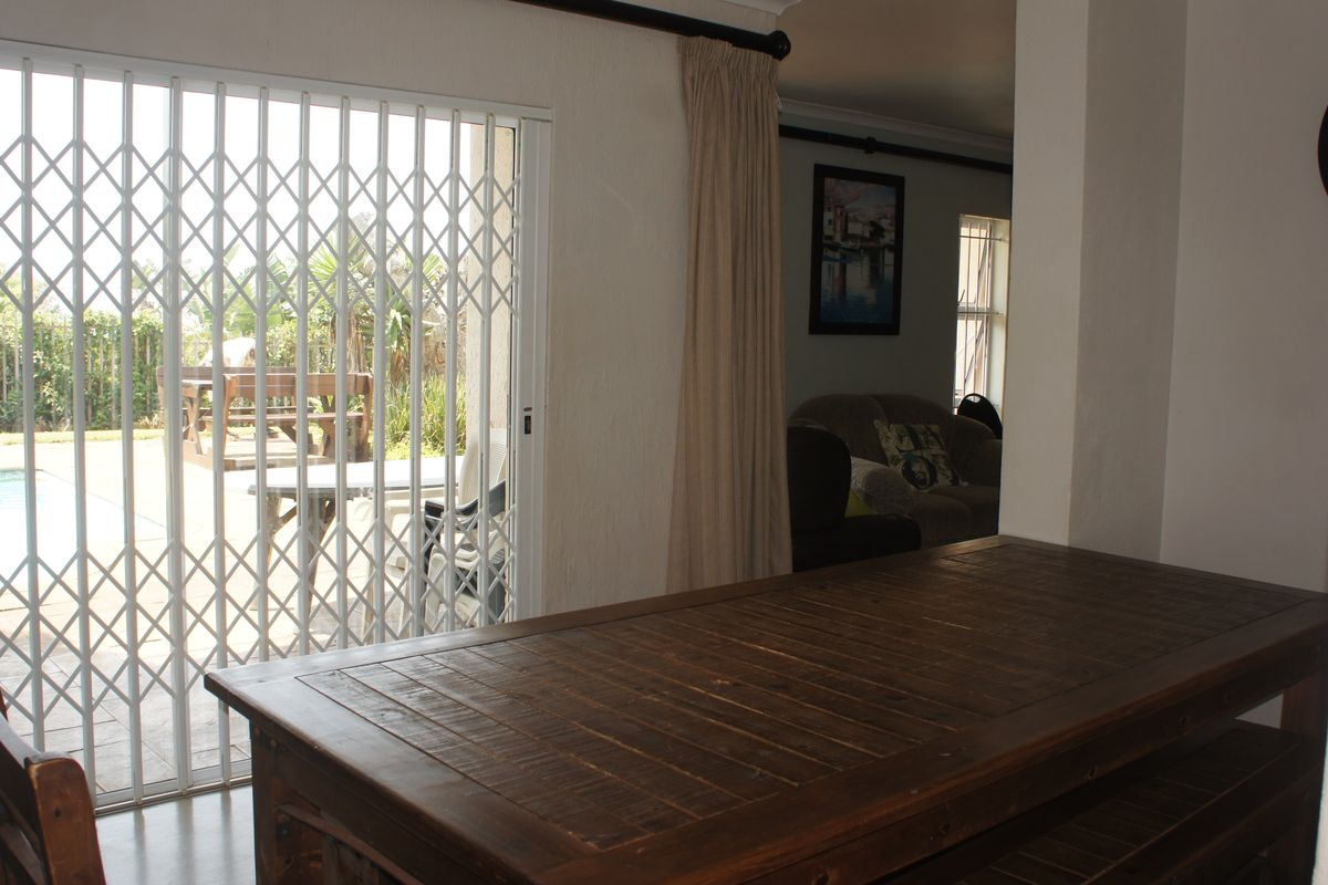 Living area featuring a sliding security gate and glass door providing direct access to the outdoor pool area.