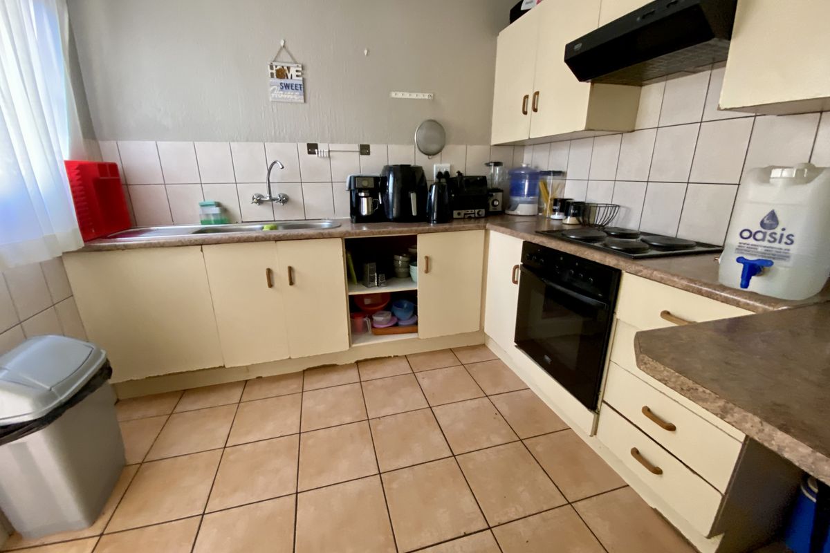 A functional kitchen featuring built-in cabinetry, laminate countertops, a built-in oven with hob, and tiled flooring, offering a practical layout for daily use.
