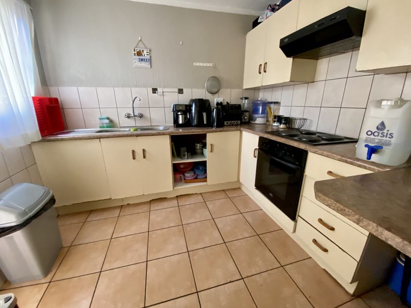 A functional kitchen featuring built-in cabinetry, laminate countertops, a built-in oven with hob, and tiled flooring, offering a practical layout for daily use.