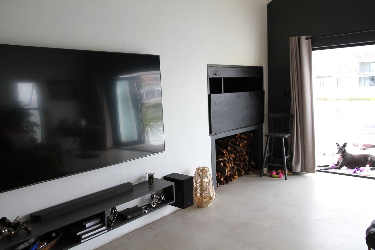 Modern living room featuring a built-in fireplace with integrated wood storage, polished concrete flooring, and direct access to an outdoor area.