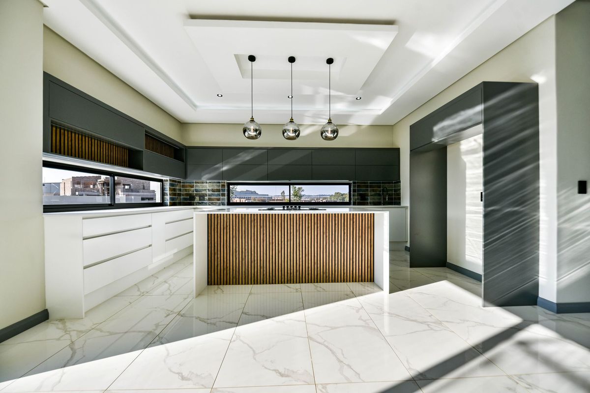 Modern kitchen featuring a central island with timber slat detailing, sleek dark cabinetry, marble-look floor tiles, and recessed ceiling lighting.