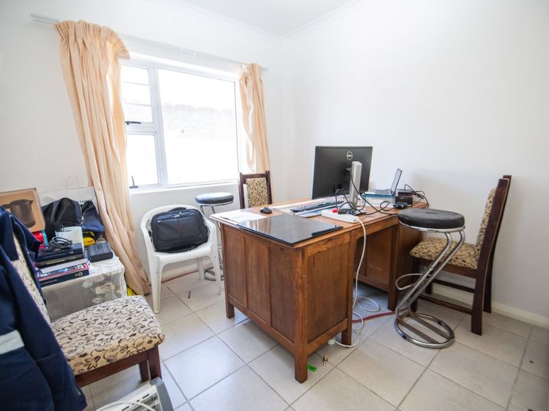 A functional home office space featuring tiled flooring and a window, providing a practical area for work or study.