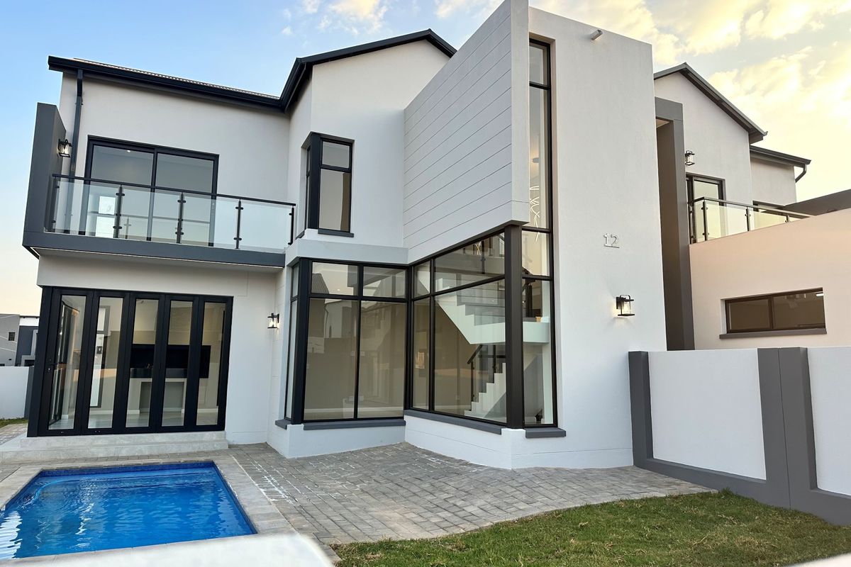 Modern double-story residence featuring a contemporary facade, large glass windows, a private swimming pool, and a paved patio area.