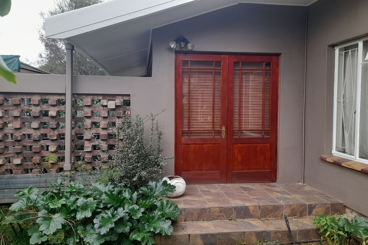 Rear patio area featuring double timber doors, tiled flooring, and a decorative brick screen wall, providing a private outdoor access point.