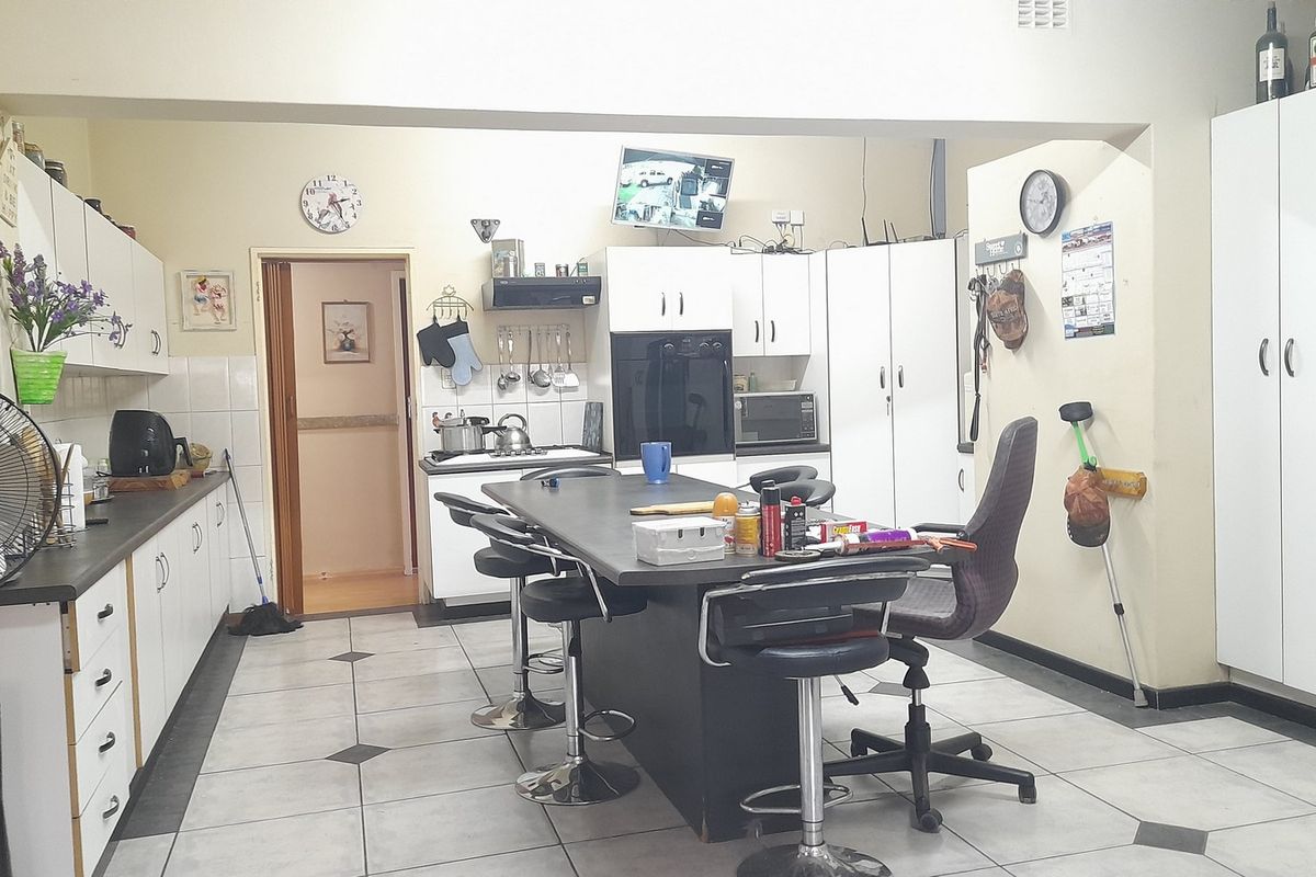 A functional kitchen featuring built-in cabinetry, a central island, tiled flooring, and integrated appliances, offering a practical layout for daily meal preparation.
