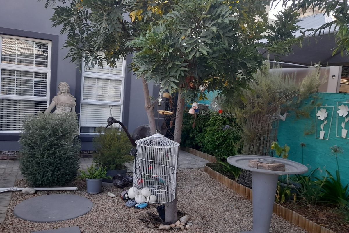 A rear garden area featuring paved sections, gravel landscaping, and a painted boundary wall with integrated decorative elements.
