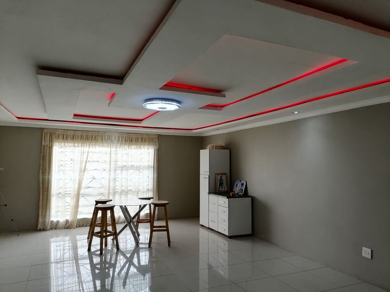 Spacious living area featuring a modern recessed ceiling design with integrated red LED accent lighting and polished tiled flooring.