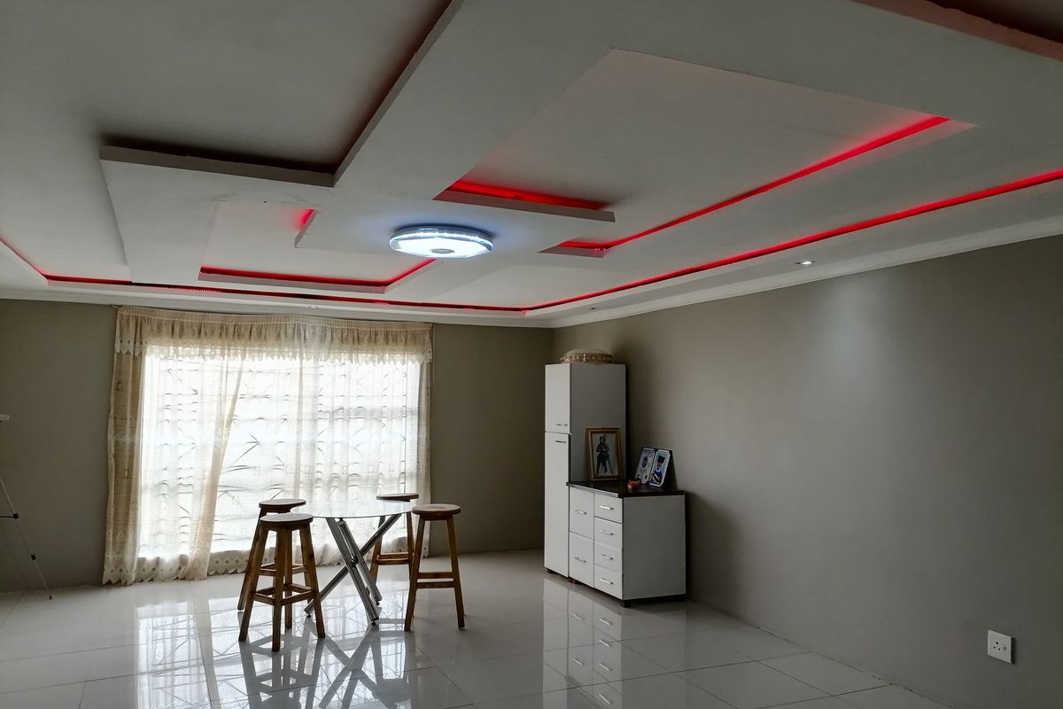 Spacious living area featuring a modern recessed ceiling design with integrated red LED accent lighting and polished tiled flooring.