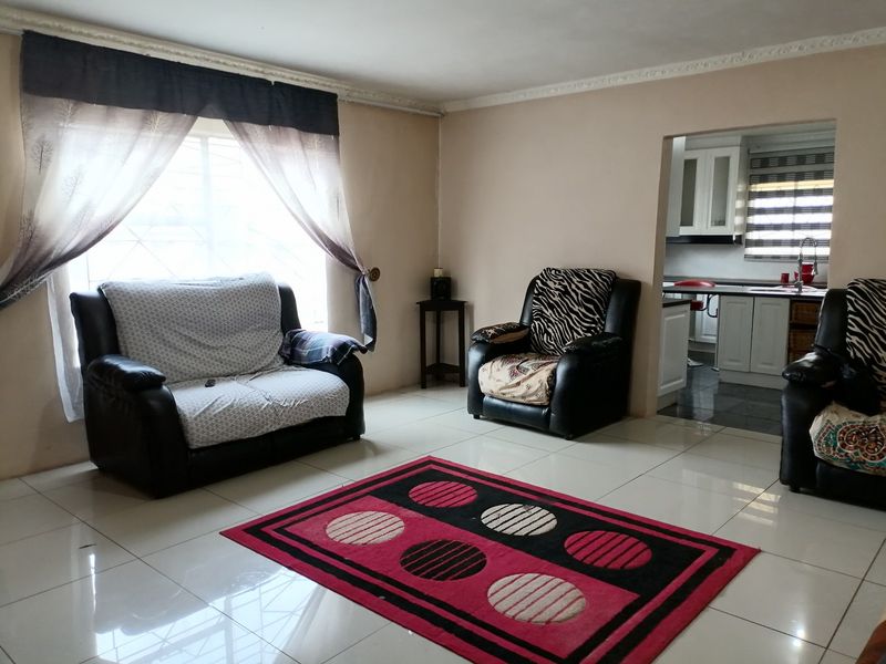 Open plan living area featuring tiled flooring and crown molding, with a direct view into the adjacent kitchen space.