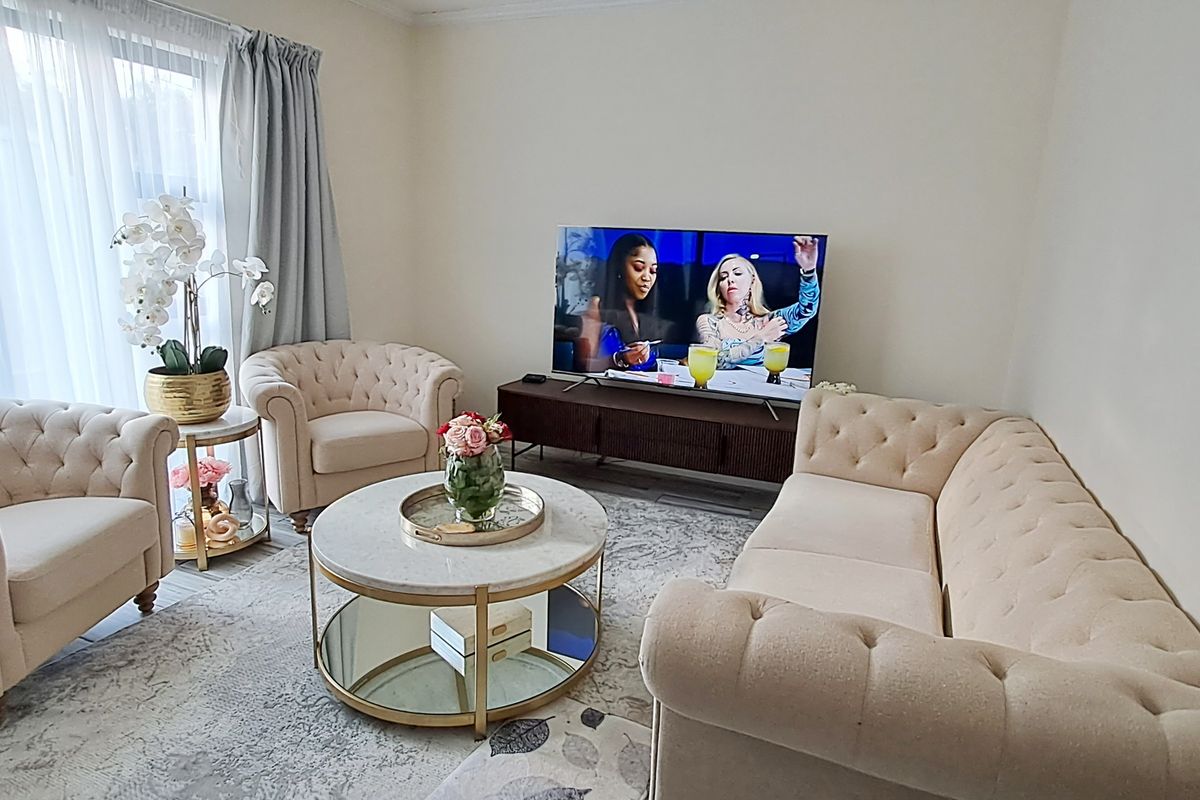 A bright and comfortable living room featuring large windows with curtains, providing ample natural light and a welcoming atmosphere.