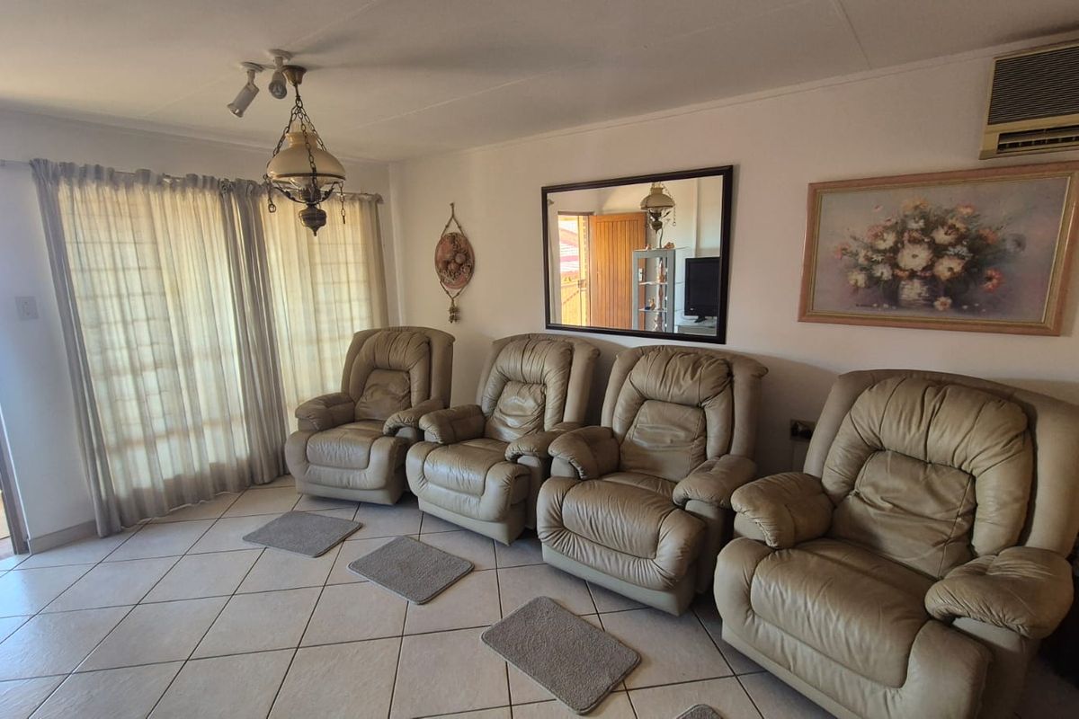 A living room featuring tiled flooring, a wall-mounted air conditioning unit, and sliding glass doors providing access to an outdoor patio area.