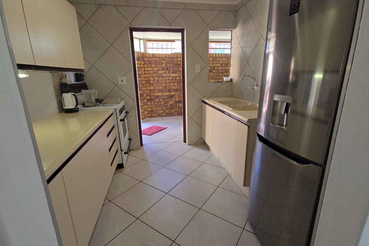 Functional kitchen featuring tiled flooring, built-in cabinetry, and a double sink, with direct access to an enclosed rear courtyard area.