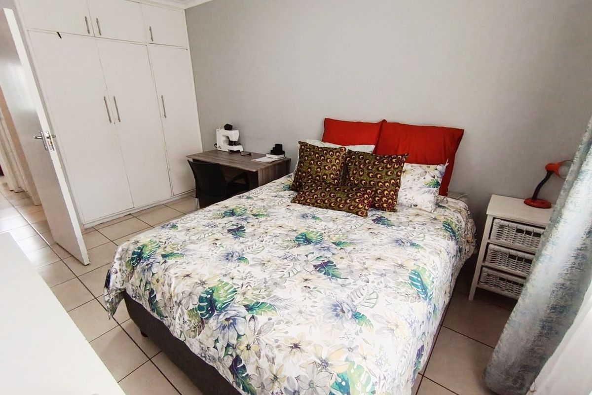 A functional bedroom featuring built-in cupboards, neutral wall finishes, and tiled flooring, providing a practical and well-maintained living space.