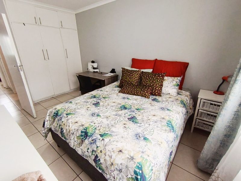 A functional bedroom featuring built-in cupboards, neutral wall finishes, and tiled flooring, providing a practical and well-maintained living space.