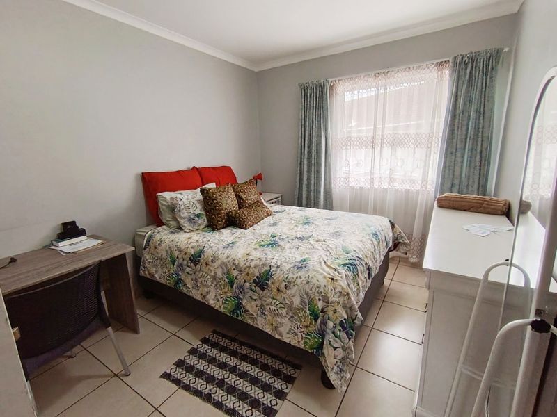 A functional bedroom featuring tiled flooring and window treatments, offering a neutral base for personalization.