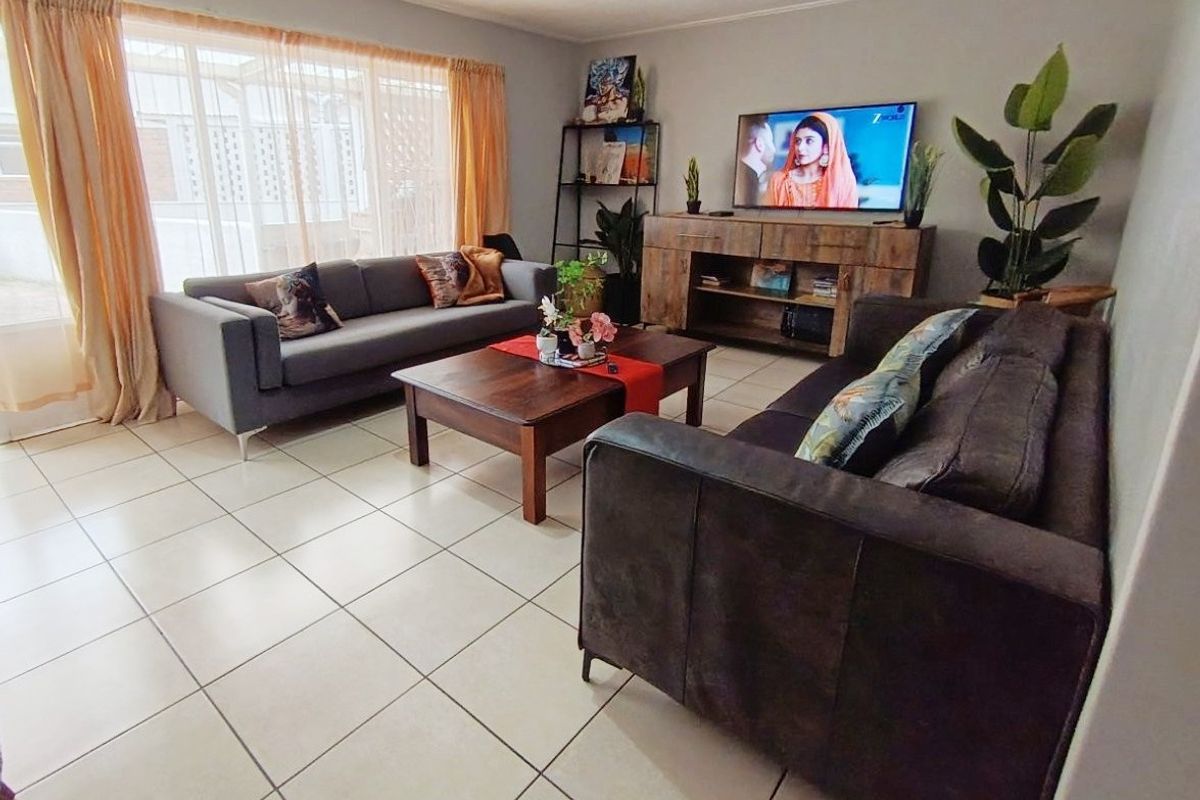 A comfortable living room featuring neutral tiled flooring and a large window that allows for natural light.