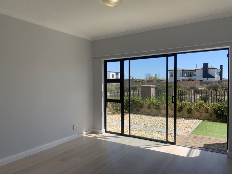 Bright and spacious living area featuring modern laminate flooring and large sliding glass doors that open onto a private garden patio.